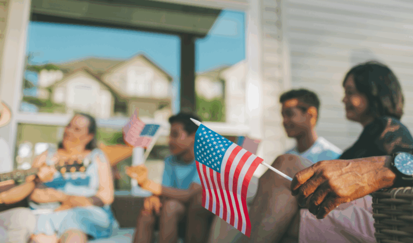 Morar Eua e SG Global Group — Bandeira americana com fundo desfocado de pessoas celebrando, representando o Dia da Independência dos EUA e o desejo de brasileiros de morar legalmente nos Estados Unidos.