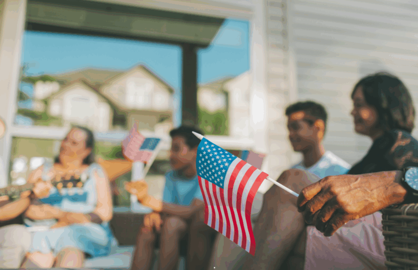 Morar Eua e SG Global Group — Bandeira americana com fundo desfocado de pessoas celebrando, representando o Dia da Independência dos EUA e o desejo de brasileiros de morar legalmente nos Estados Unidos.